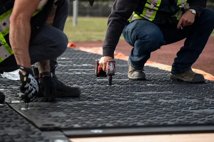 Workers installing interlocking MaxiTrack ground protection mats to create a durable, hand-deployable temporary access surface on a job site