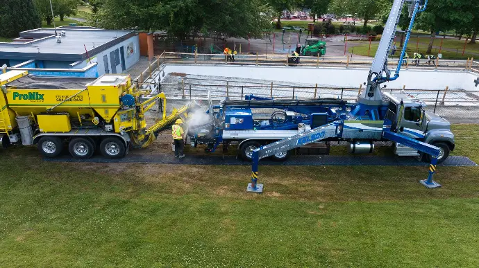 Heavy equipment and trucks operating on MaxiTrack ground protection mats to create a stable, non-damaging access route during a construction concrete pour.